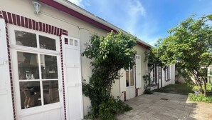 Ein Haus mit einem gefliesten Patio, einer weißen Tür und einem Fenster mit Blick ins Innere.