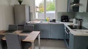 Eine moderne Küche mit Essbereich, einem Einbauofen, einer Kaffeemaschine und einem Fenster mit Blick nach draußen.