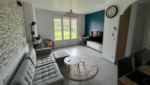 Ein modernes Wohnzimmer mit einem Ecksofa, einem runden Couchtisch und einem TV-Bereich mit blauer Akzentwand.