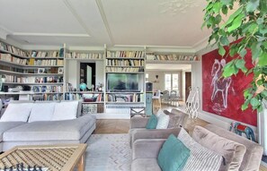 A spacious living room with a large bookshelf, two sofas, a coffee table, and a TV. - A PERFECT BLEND OF COMFORT, ELEGANCE & TRANQUILLITY AT BLVD SAINT GERMAIN (Paris)