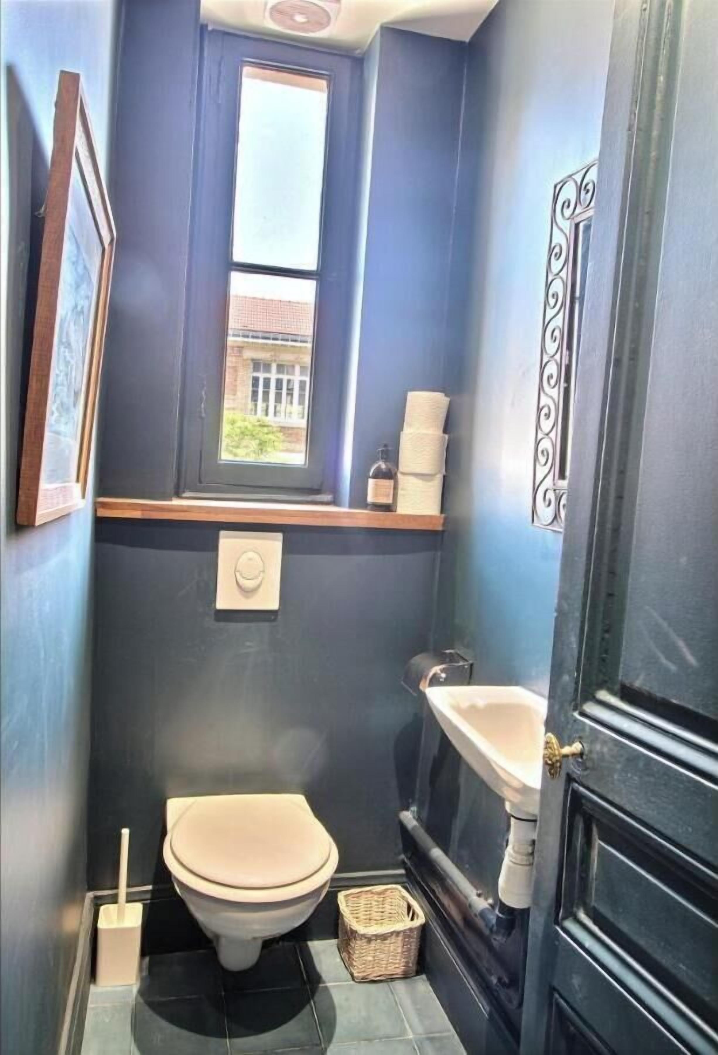 A compact bathroom with a toilet, sink, and window.