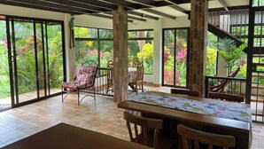 A spacious dining area with a table and chairs, large windows offering a view of lush greenery, and a staircase leading to an upper level. - Full lodging, lookout point  (Mirador)