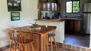 A kitchen with wooden cabinets, a stainless steel refrigerator, and a dining area with a wooden table and chairs. - Full lodging, lookout point  (Mirador)