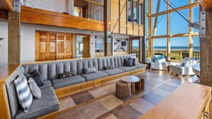 A spacious living area with a large sofa, a round table, and a view of the sea. - Villa Seamone | Beachfront, Pet Friendly (Galveston)