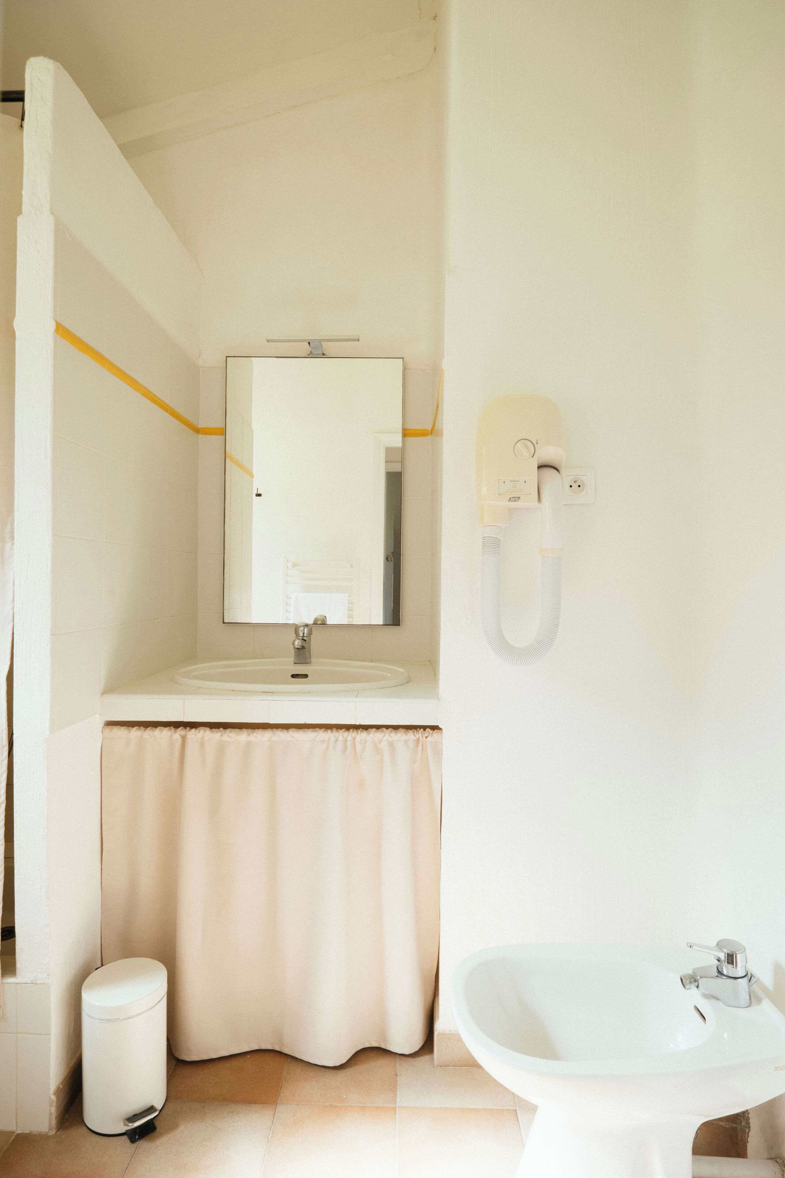 A bathroom with a sink, mirror, shower, and bidet.