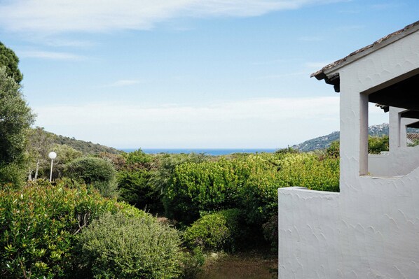 A white building with a view of a vineyard and distant mountains.