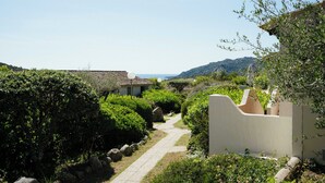 A pathway leading to a building with a view of the sea and hills. - Résidence Les Hauts de Santa Giulia (Porto-Vecchio)