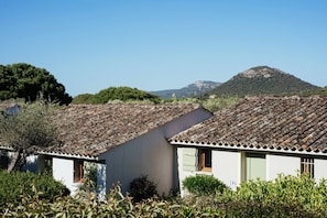 A traditional building with a tiled roof, surrounded by greenery and a mountain in the background.