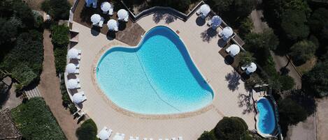 An aerial view of a heart-shaped swimming pool surrounded by lounge chairs and umbrellas.