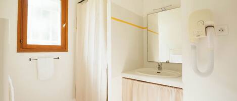 A bathroom with a wooden-framed window, a white sink, a mirror, and a shower curtain.