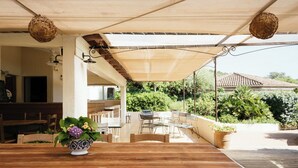 An outdoor patio with a wooden table, chairs, and a decorative bowl with flowers. - Résidence Les Hauts de Santa Giulia (Porto-Vecchio)