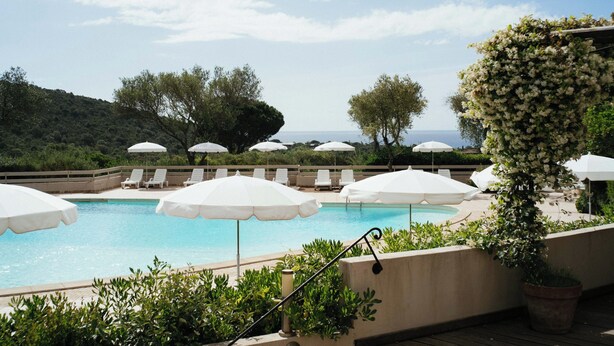 A pool area with white umbrellas, lounge chairs, and a view of the sea. - Résidence Les Hauts de Santa Giulia (Porto-Vecchio)