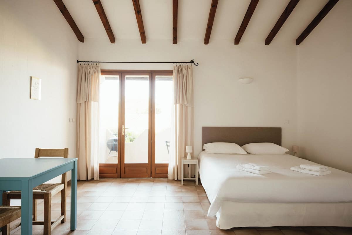 A bedroom with a bed, a table, and a chair.