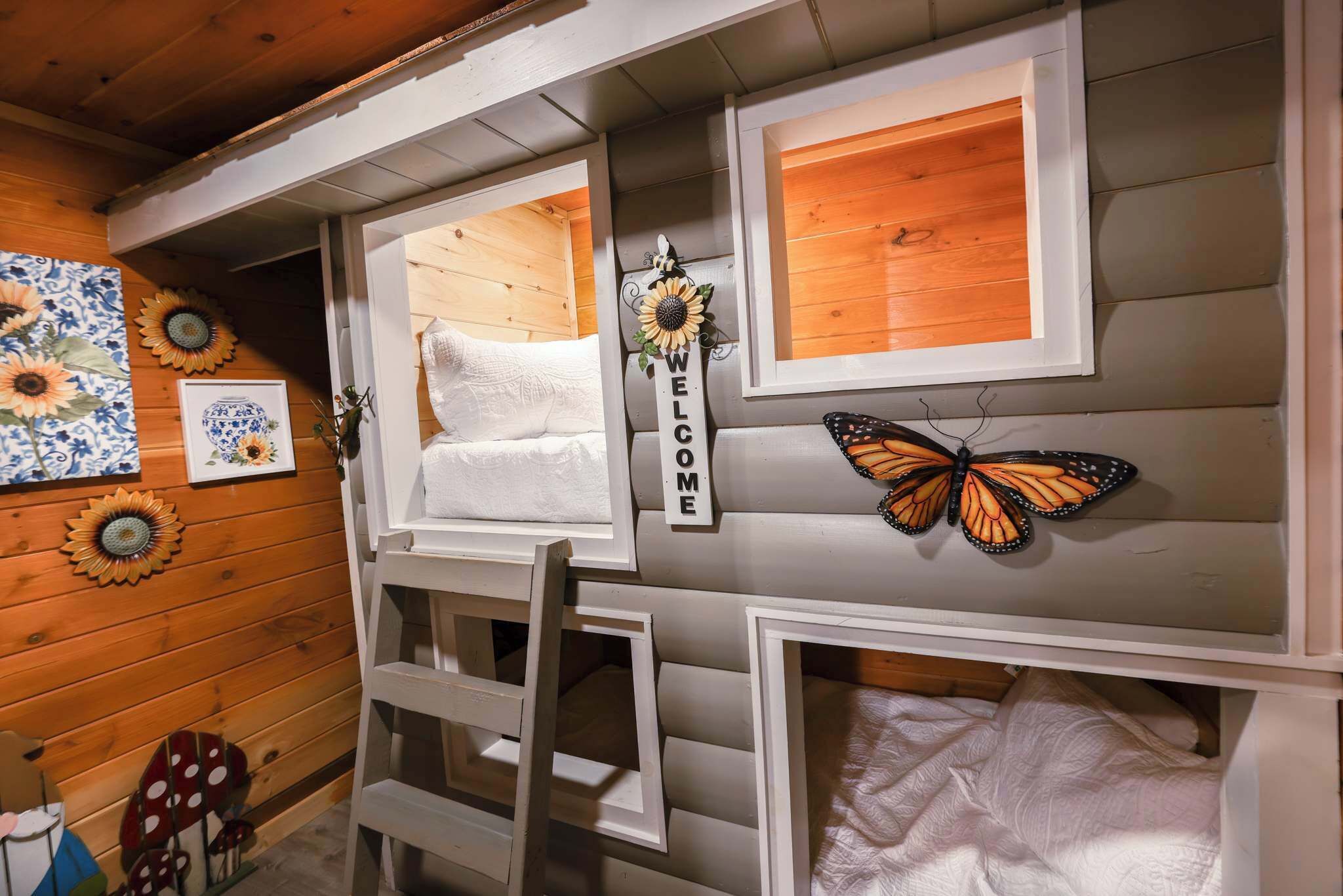 A room with a bunk bed, a ladder, a welcome sign, and decorative sunflowers.