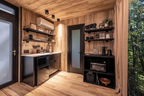 A compact kitchen with wooden paneling, built-in shelves, and a refrigerator. - Brand New Mirror House | Sauna | Hot Tub | Stargazing (Sevierville)
