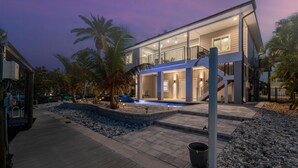 Ein modernes, zweistöckiges Haus mit Balkon, Pool und einer Holzterrasse.