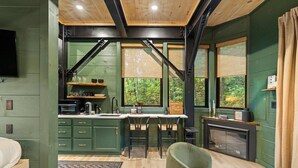 Un'accogliente cucina in stile baita con zona pranzo, pavimenti in legno e ampie finestre che si affacciano sulla foresta.