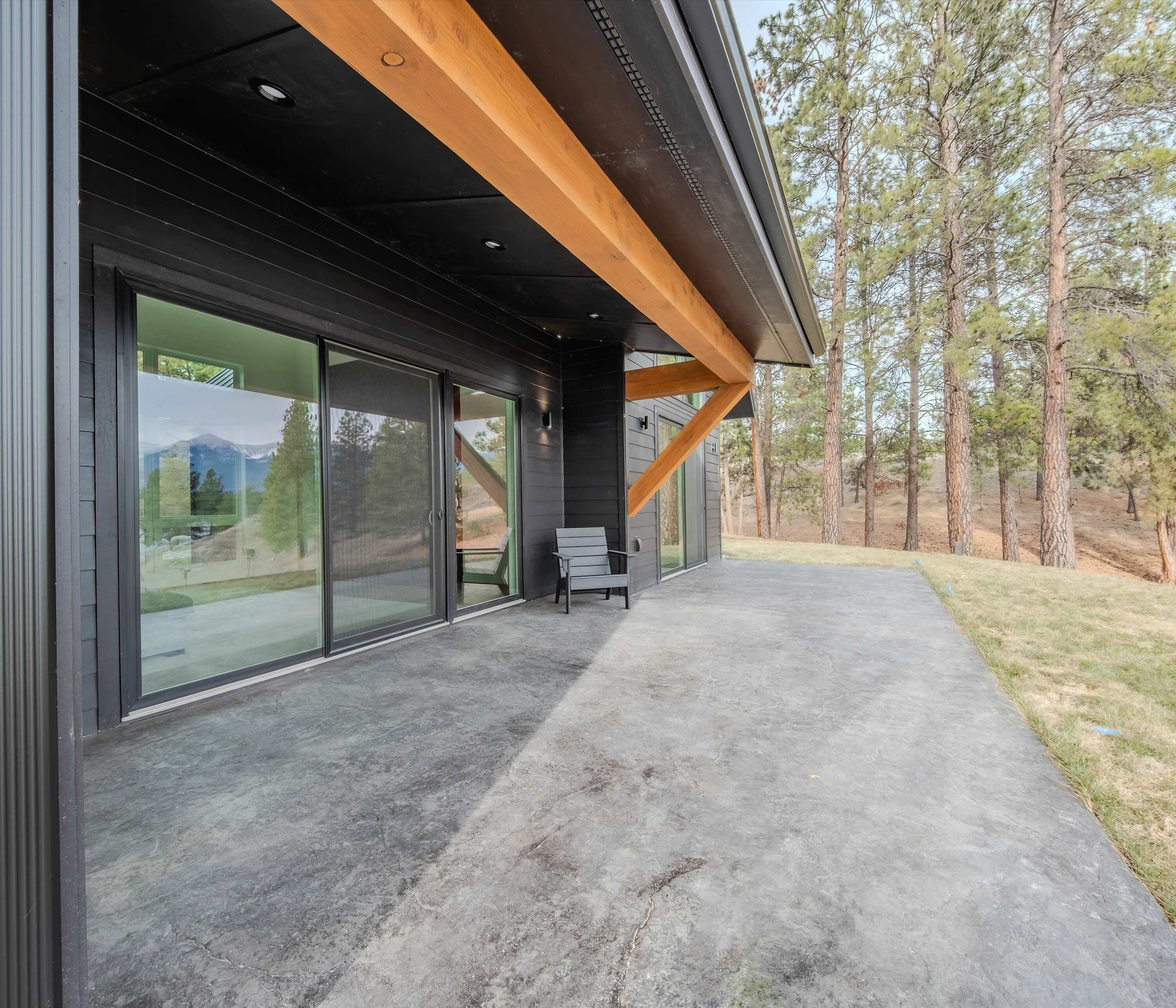 A modern building with large glass doors and a concrete patio.