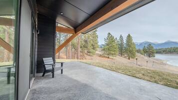 A modern outdoor patio with a concrete floor, wooden beams, and a bench.