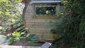 A wooden cabin with a window, surrounded by greenery. - Col de la Faucille Tonneau (Mijoux)