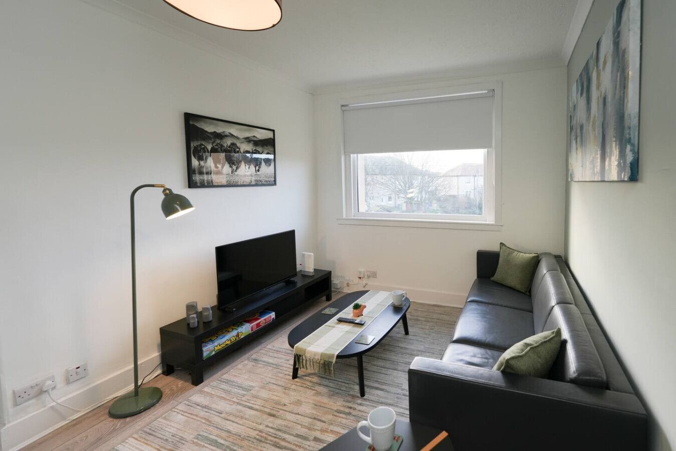 Un salon moderne avec un téléviseur à écran plat, un canapé, une table basse et un lampadaire.