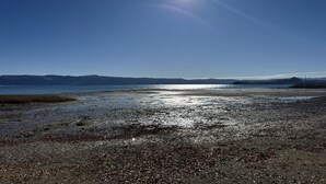 Een strand met een heldere lucht en verre bergen.