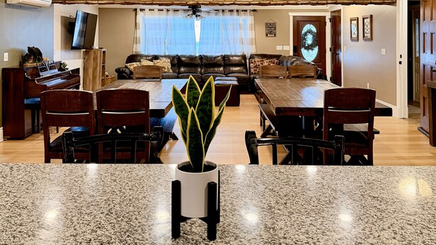 Un salón amplio con una pared de acento de piedra, un comedor con mesa de granito y una zona de estar acogedora.