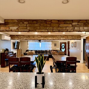 A spacious living room with a stone accent wall, a dining area with a granite table, and a cozy seating arrangement.