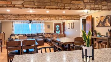 A spacious living area with a stone ceiling, a dining table, and a kitchen area with granite countertops.
