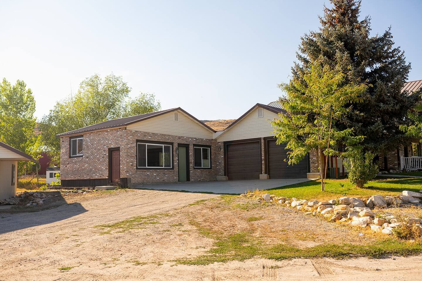 A residential house with a brick exterior, two garage doors, and a driveway leading to the entrance.