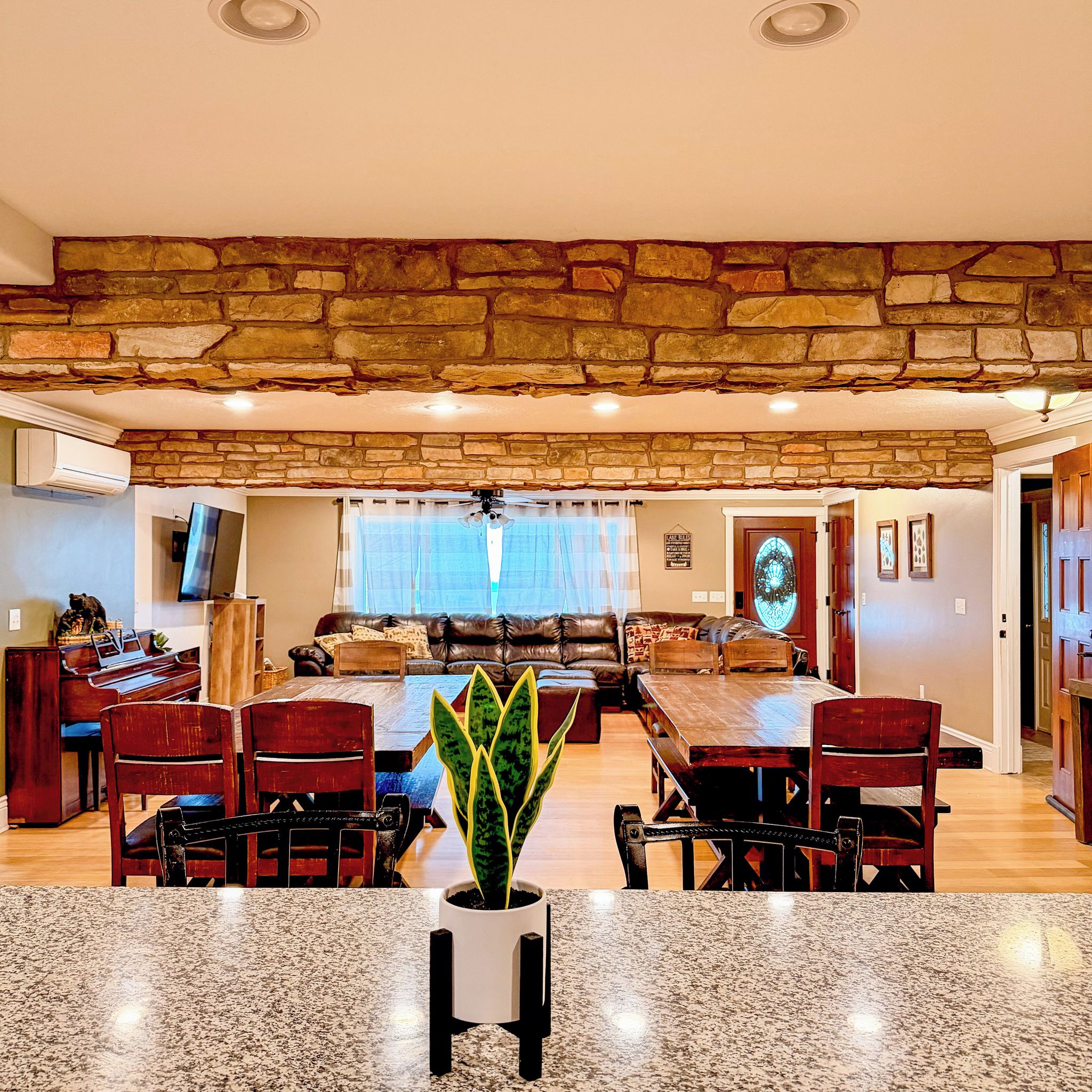 A spacious living room with a stone accent wall, a dining area with a granite table, and a cozy seating area with a fireplace.