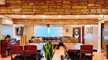 A spacious living room with a stone accent wall, a dining area with a granite table, and a cozy seating area with a fireplace.