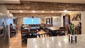 Una cocina amplia con encimeras de granito, una pared de acento de piedra y un comedor con piano.