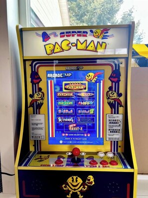 A Pac-Man arcade game machine with a selection of games displayed on the screen.