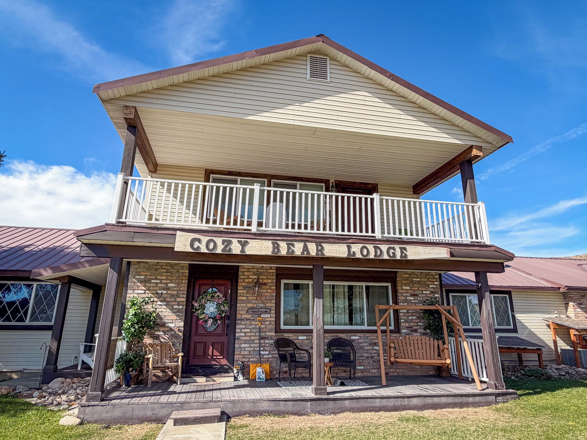 A two-story building with a balcony and a sign that reads 'COZY BEAR LODGE'.