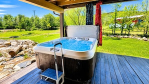 Un jacuzzi en una terraza de madera con vistas a un paisaje verde.
