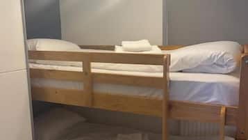 Una cama litera con estructura de madera, ropa de cama blanca y una lámpara en el techo.