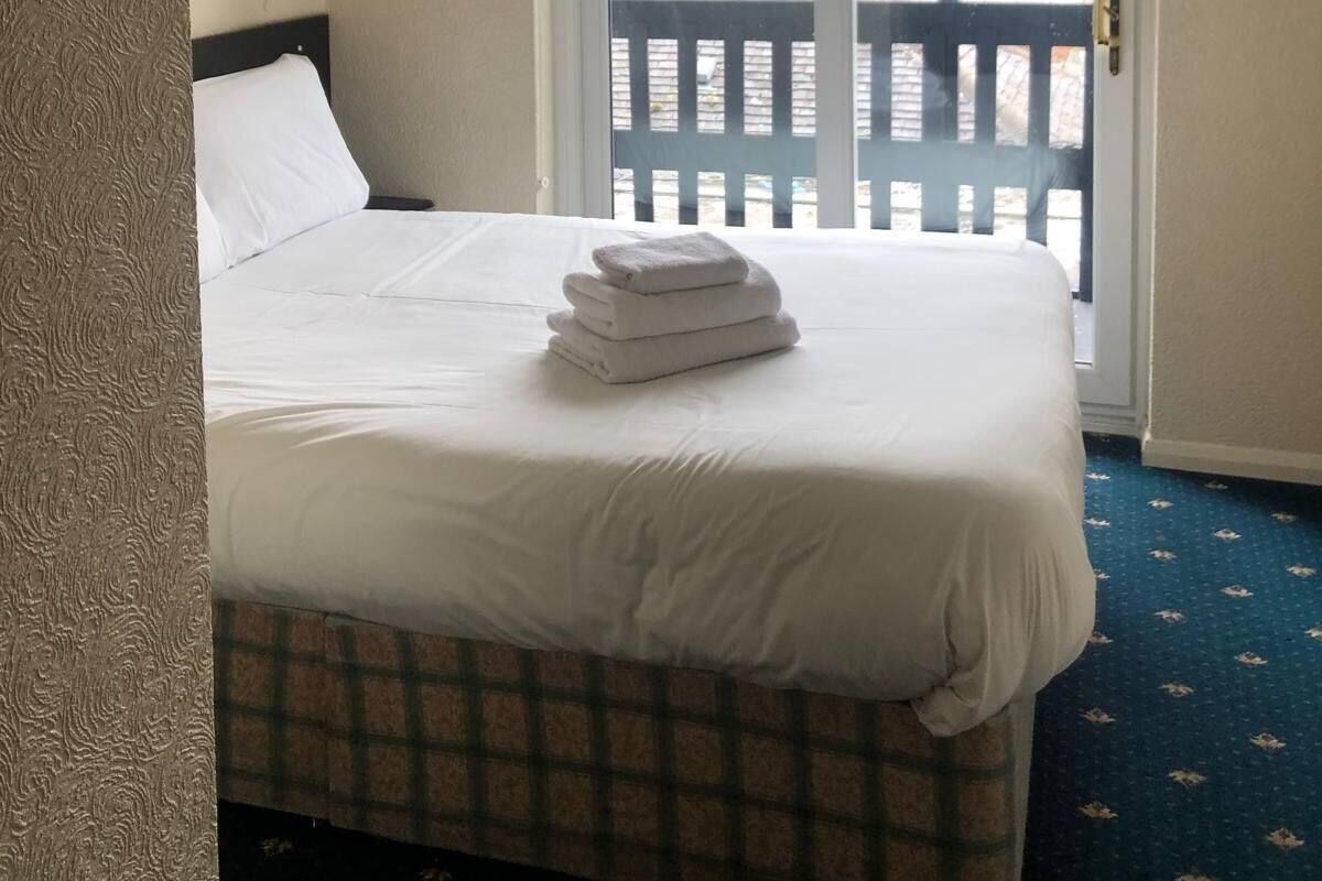 A hotel room with a bed, a window, a door, and a ceiling light.