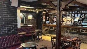 A bar area with a stone wall, wooden furniture, and a brass ceiling fan. - Moorville Hall Hotel (Stoke-on-Trent)