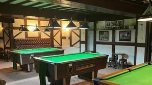 A pool hall with multiple pool tables, a cushioned seating area, and framed pictures on the walls. - Moorville Hall Hotel (Stoke-on-Trent)