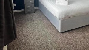 A bedroom with a large bed, a nightstand, a dresser, and a textured blue wall. - Moorville Hall Hotel (Stoke-on-Trent)
