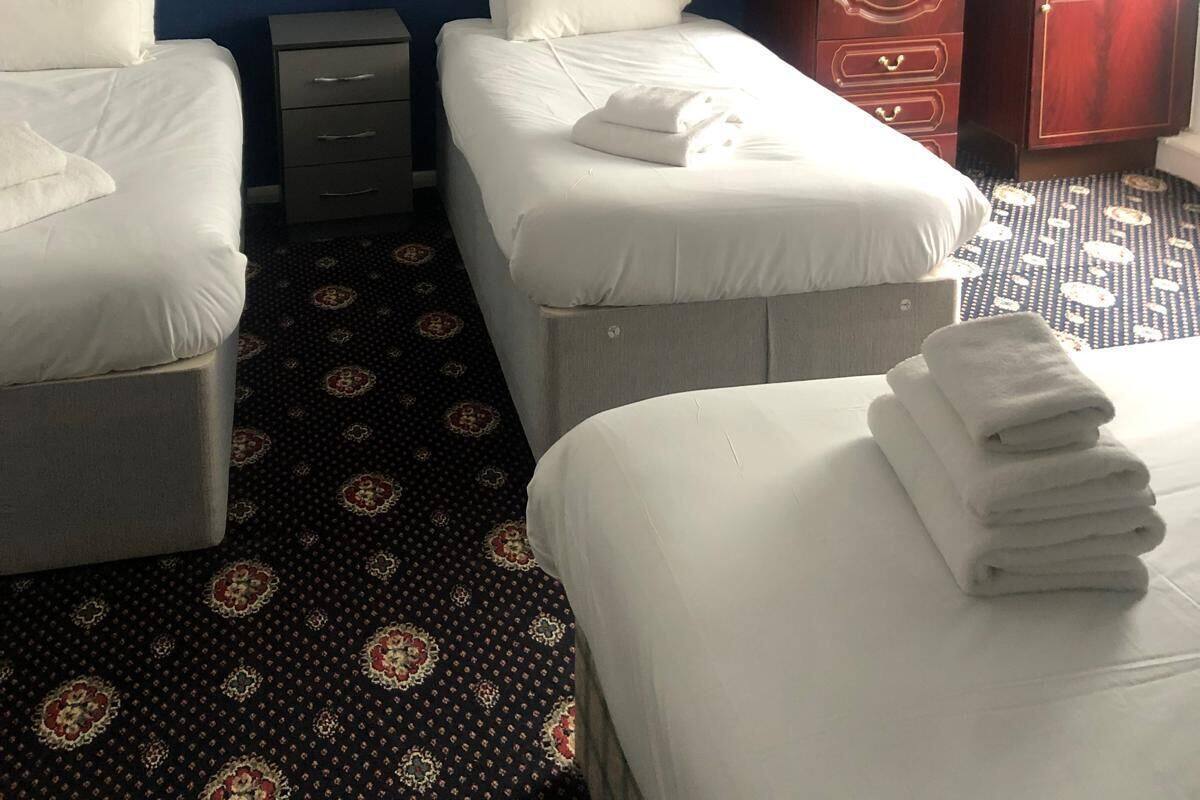 A hotel room with two beds, a dresser, a wardrobe, and a patterned carpet.
