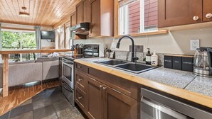 Eine moderne Küche mit Holzausbau, Granit Arbeitsplatten, einer doppelten Spüle und einem eingebauten Backofen.