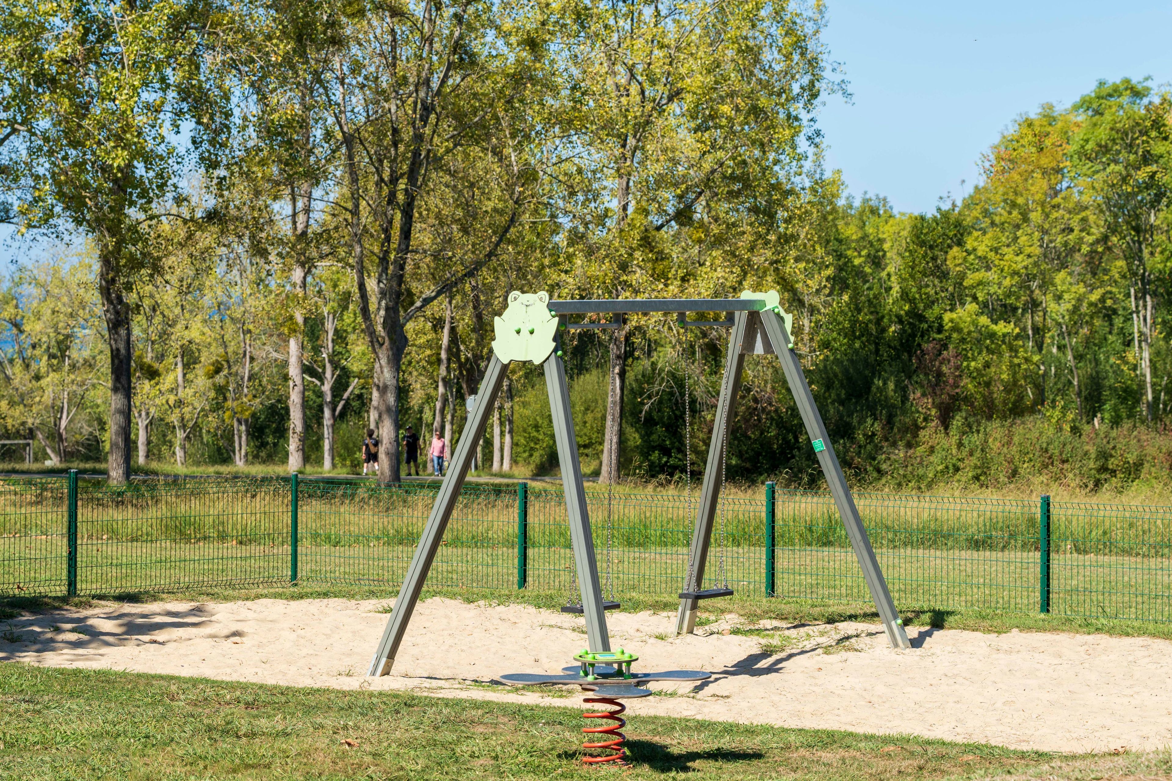 A playground with a swing set and a seesaw.