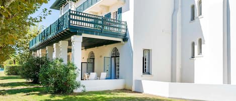 Un bâtiment à deux étages doté d’un balcon, d’une terrasse couverte et d’un jardin.