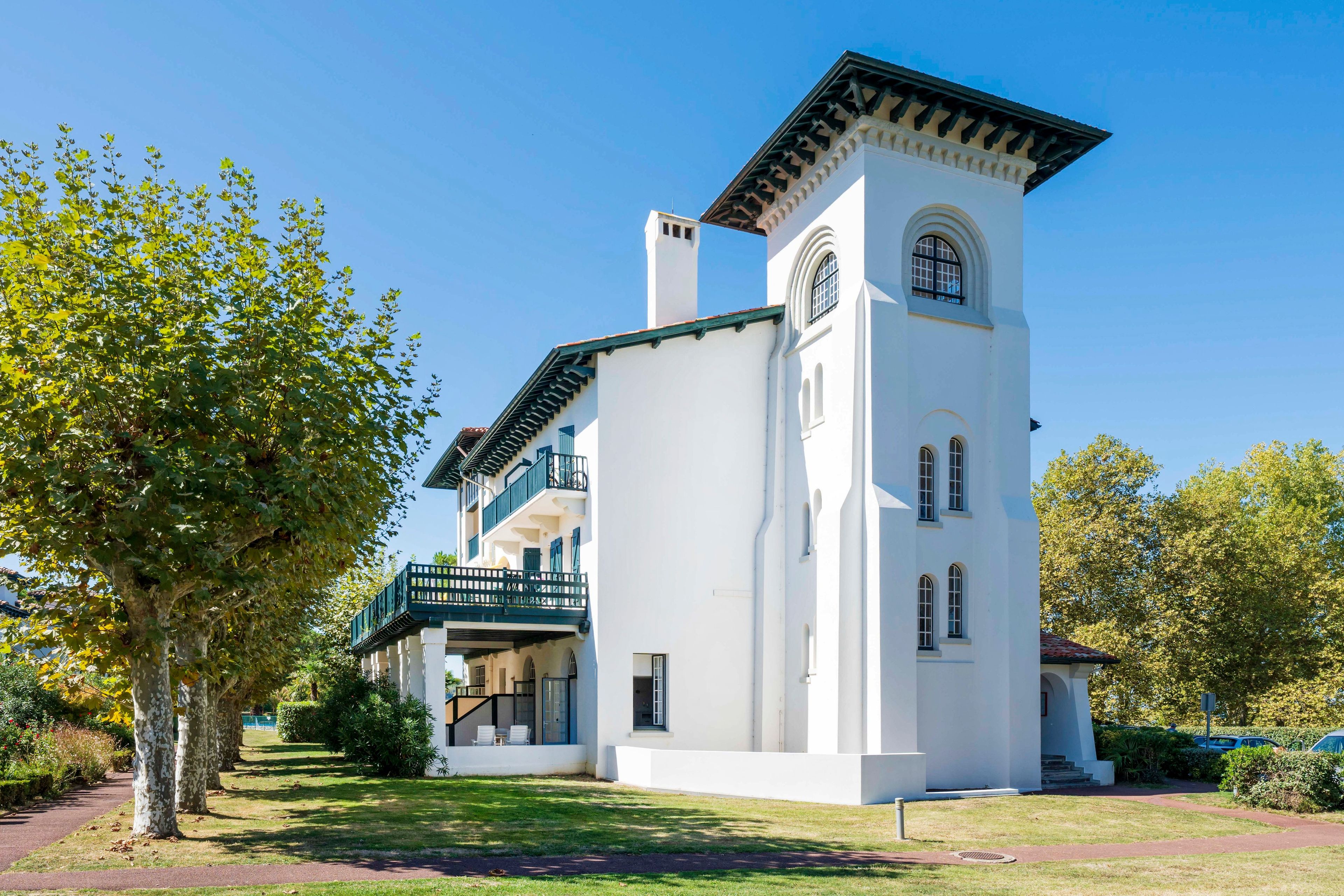 Un edificio blanco con una torre, un balcón y un camino.