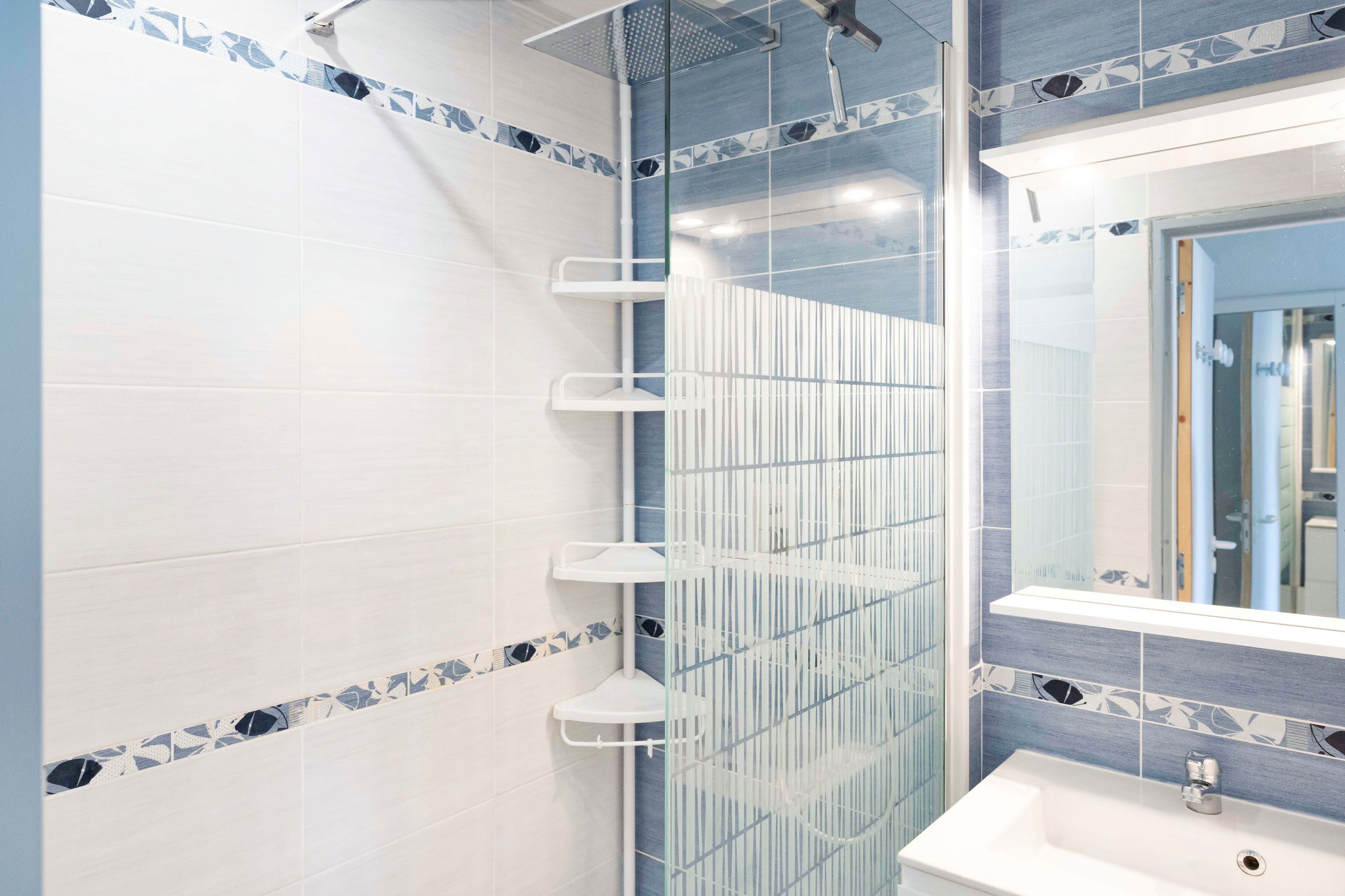 Une salle de bain avec une douche, un lavabo et un miroir.