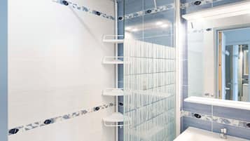 Un baño con ducha, lavamanos y espejo.