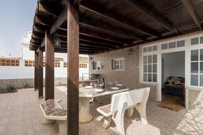 An outdoor patio with a stone table and chairs, a wooden pergola, and a view of the cityscape. - Home2Book Peaceful Terrace Oasis Fuerteventura (Pajara)