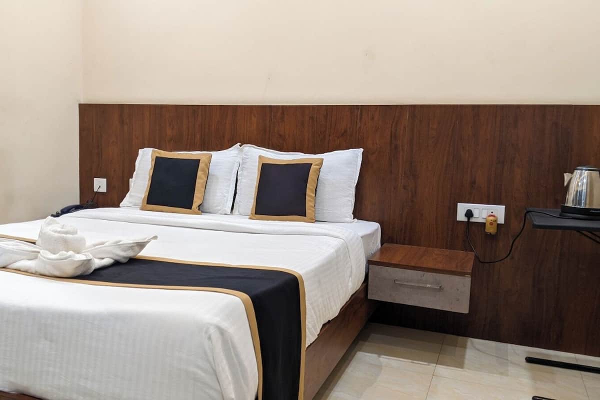 Una habitación de hotel con cama, mesita de noche y velador.